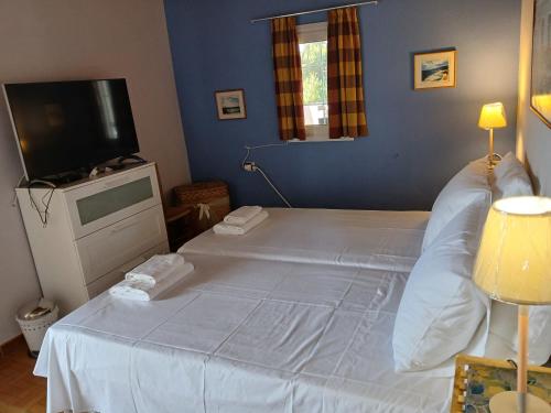a bedroom with a large white bed with a flat screen tv at sunset in Raches