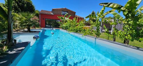 une piscine avec de l'eau bleue devant une maison dans l'établissement Villa Pessac jardin luxuriant et piscine chauffée, à Pessac