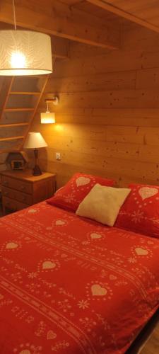 - une chambre avec un lit rouge dans une cabane en rondins dans l'établissement Chalet-nature, à Bolquère-Pyrénées 2000