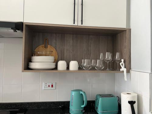 a kitchen with a shelf with plates and wine glasses at Sarona LoLa A103 Kappa in Gaborone