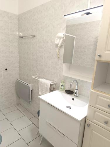 une salle de bain blanche avec un lavabo et un miroir dans l'établissement le centre de saint florent, à Saint-Florent