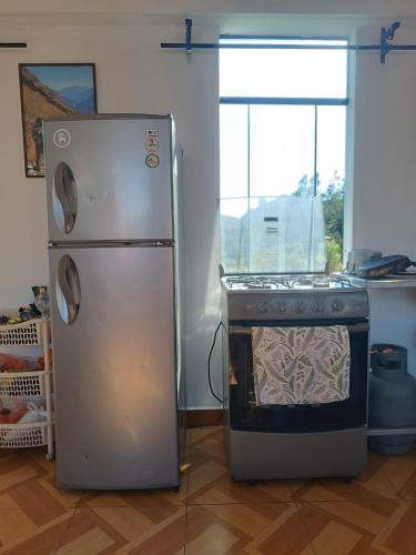 a refrigerator and an oven in a kitchen at Vertigo Climbing Hostel in Urubamba