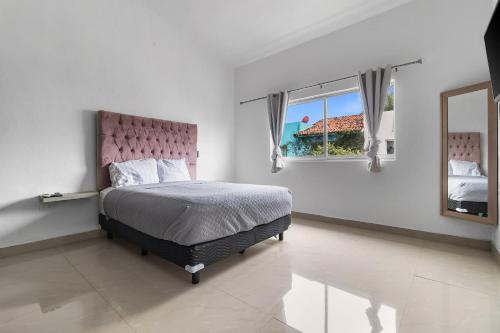 a bedroom with a bed with a pink headboard and a mirror at Casa Encanto - 3Bdr, 2.5bath w/Jacuzzi and Parking in Puerto Vallarta