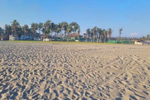 a sandy beach with palm trees in the background at Paktinemi Diamante Fantastic View Beach Club in Acapulco