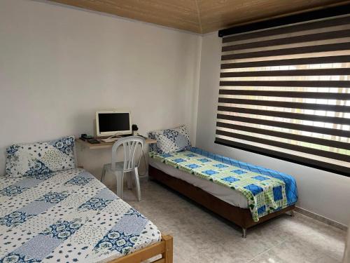 una camera da letto con due letti e una scrivania con un computer di Alojamiento campestre en Restrepo a Restrepo