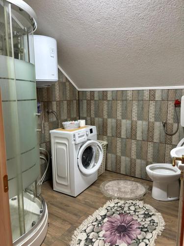 a bathroom with a washing machine and a toilet at Apartman Salus in Tuzla