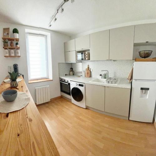 a kitchen with white cabinets and a wooden floor at Le Cocon de KENNA au centre du bourg in Dompierre-sur-Besbre