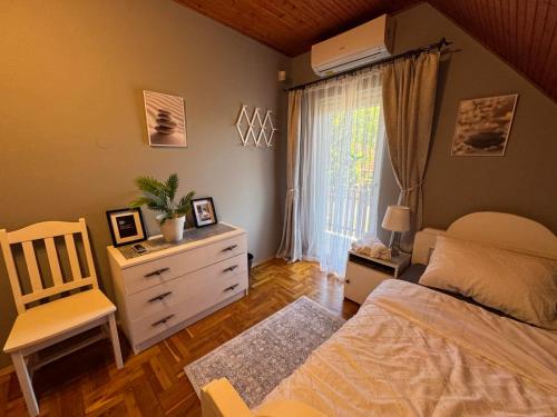 Un dormitorio con una cama y una cómoda y una ventana. en MIMÓZA Nyaralóház, en Tiszafüred