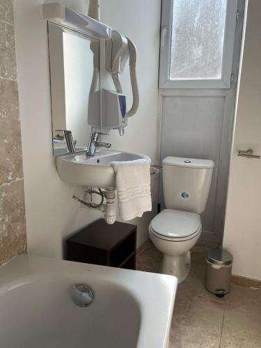 a bathroom with a sink and a toilet and a mirror at Hôtel de la paix in Limoges