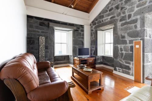 a living room with a leather couch and a stone wall at Casa da Torre in São João