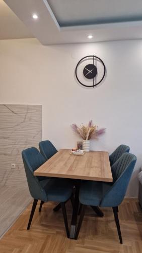 a dining room with a wooden table and blue chairs at Afrodita Lux East Sarajevo in Lukavica