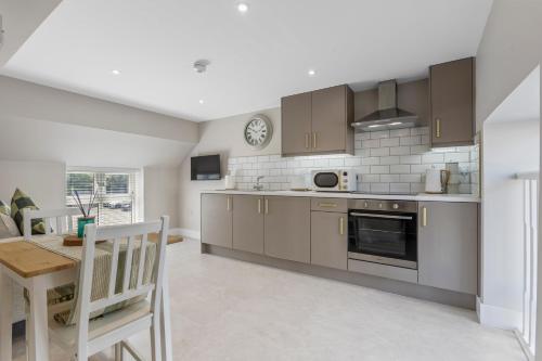 a kitchen with brown cabinets and a table and a dining room at The Mail Rooms Limavady - Boutique Stays in Limavady