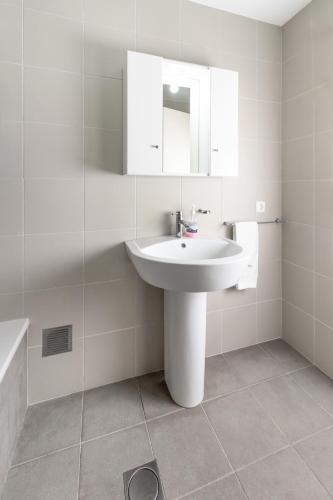 a white bathroom with a sink and a mirror at Casa da Torre in São João
