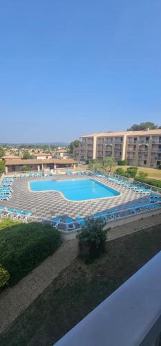 une grande piscine avec des chaises bleues et un bâtiment dans l'établissement La Dolce Vita, à Balaruc-les-Bains