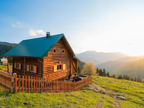 a log cabin on a hill with a fence at Prokletije Lodge in Plav