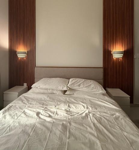 a bedroom with a white bed with two night stands at ONYX F64-2BHK cozy full furnished in heart of Muscat in Muscat