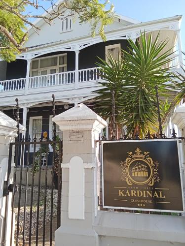 a sign in front of a white house at Kardinal guesthouse on 44 St Phillips street in Gqeberha