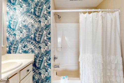 a bathroom with a shower with a white shower curtain at Lagoon Landing #302 in Gulf Shores