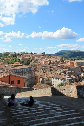 Dos personas sentadas en las escaleras mirando una ciudad. en Minimetro Suite with Easy Access to Perugia Center & Free Parking, en Perugia