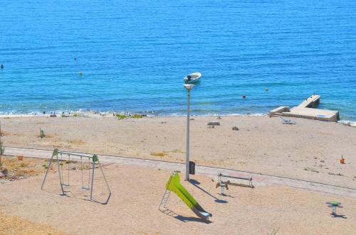 a beach with swings and a light pole and the water at Apartments Barbati in Novalja