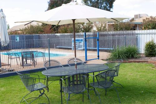 a table with an umbrella next to a pool at A Line Motel in Griffith