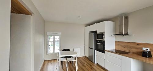 une cuisine avec des armoires blanches, une table et une cuisinière dans l'établissement Le Chatenay - Appartement Angers - WIFI Gratuit, à Angers