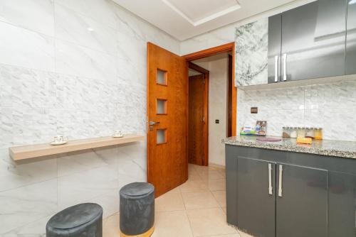 a kitchen with black stools and a wooden door at Élégant appartement F3 au centre in Kenitra