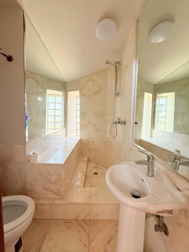 a bathroom with a sink and a tub and a toilet at Luxury SeaView Villa Pool-Bbq in Neos Voutzas