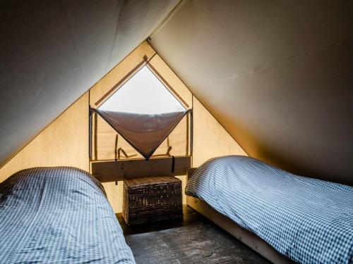 Un dormitorio con dos camas y una ventana. en Lodge Tent in Callantsoog by Dunes, en Callantsoog