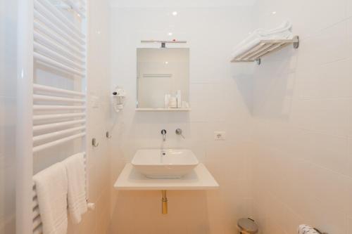 a white bathroom with a sink and a mirror at Aria Rooms in Procida