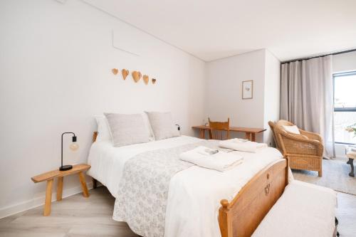 a white bedroom with two beds and a chair at Olyfberg Rus in Paarl
