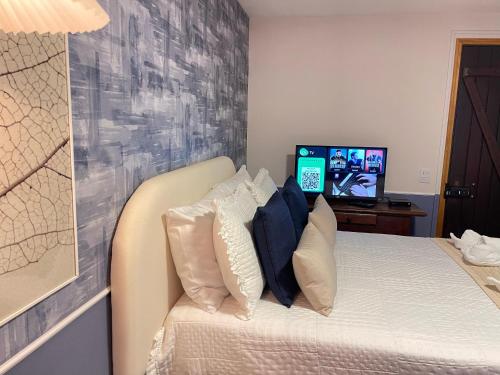 a bedroom with a bed with pillows and a tv at Pousada Flor de Lua Monte Verde in Monte Verde