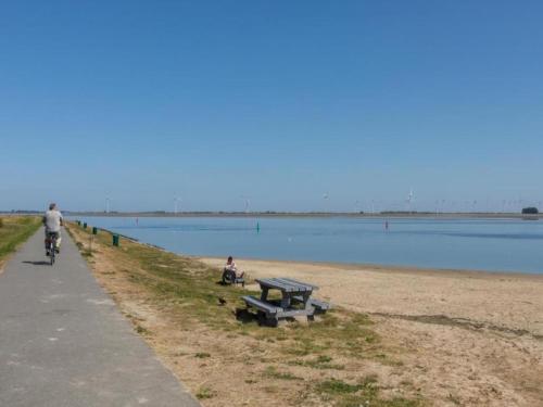 a man riding a bike next to a bench on the beach at Penthouse in Sint-Annaland by the Beach in Sint Annaland