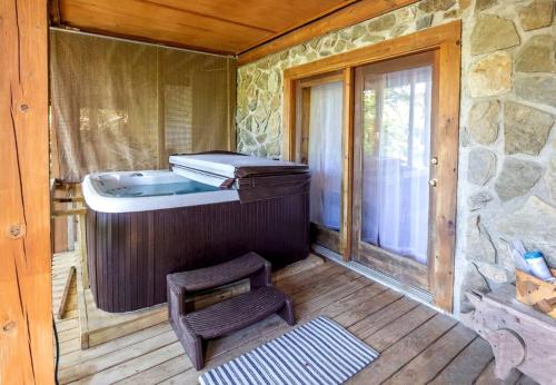 a room with a soaking tub and a chair on a porch at Cabin In Lake Lure Getaway in Lake Lure