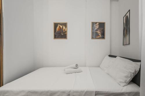 a white bed in a room with three pictures on the wall at Interbelic Villa close to Old Town in Bucharest