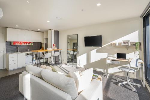 a living room with a white couch and a kitchen at Stylish Apartment in Melbourne in Melbourne