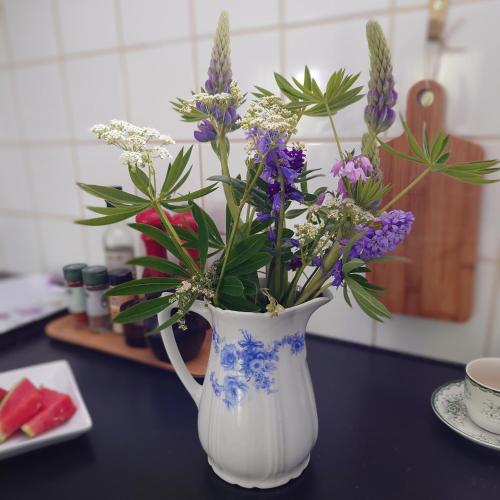 a white vase filled with purple flowers on a table at Ales BnB Lägenheten in Löderup