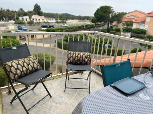deux chaises et une table sur un balcon dans l'établissement Au balcon de la mer, appartement à Marseillan plage, à Marseillan