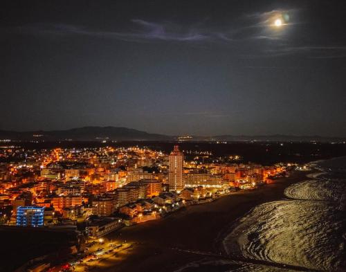 a view of a city at night with the moon at MARECHIARA Apartment - Independent ground-floor unit in central Nettuno with private patio, just 50 m from the sea and steps from the train station in Nettuno