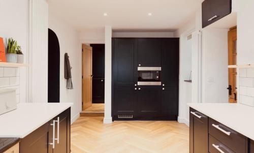 eine Küche mit schwarzen Schränken und einer schwarzen Tür in der Unterkunft A Beautiful 3 Bedroom 17th Century Stone cottage in Llanddyfnan