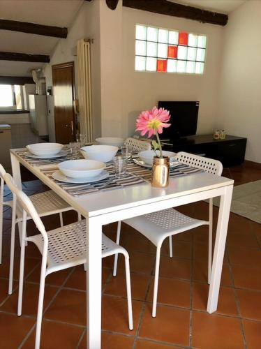 een witte tafel met stoelen en een vaas met een bloem erop bij Mansarda la Graziosa in Rimini