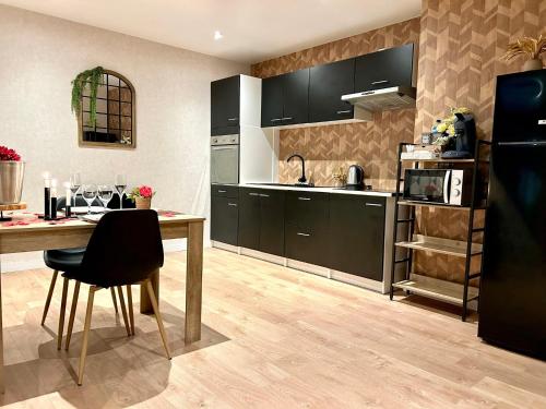 une cuisine avec des armoires noires et une table avec des chaises dans l'établissement Vénus - Maison de charme, zen avec SPA, à Plouray