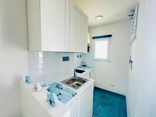 a kitchen with white cabinets and a sink at Acquario - Immobilevante in Ponza