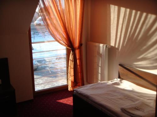 a bedroom with a window with an orange curtain at Gościniec Europejski in Miedziana Góra