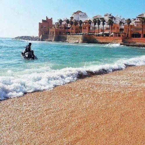 a man riding a motor cycle on the beach at Sunny modern Apartment- Ocean & Pool view in Al Mansouria in Mansouria