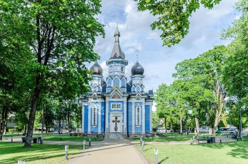 een blauw gebouw in een park met bomen bij Nemunas A respite Studio 8 in Druskininkai