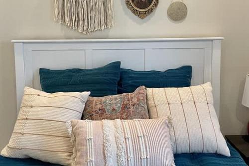 a bed with blue pillows and a white head board at River Access Firepit BBQ Pet Friendly Sleeps 8 in Kyle