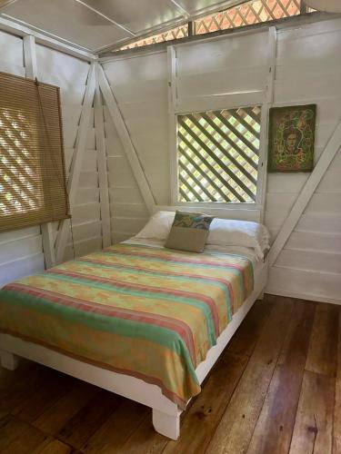 a bedroom with a bed in a room with windows at Caribbean Flow in Puerto Viejo