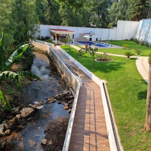 a walkway over a stream in a yard at Casa del bosque in Cerro Gordo