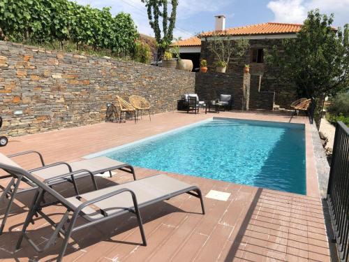 a swimming pool with chairs and a brick wall at Quinta do Barrocal - Casa de Campo in Peso da Régua